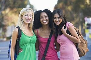 Three women outdoors standing with arms around each other (selective focus)