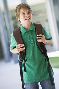 Student standing outside school smiling (selective focus)