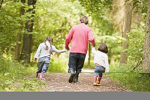 Father and daughters walking on path holding hands