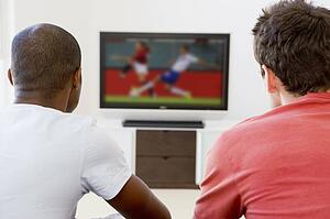 Two men in living room watching television
