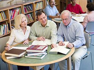 Three people in library with notepads (selective focus)