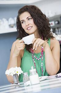 Young woman sitting at a table drinking tea