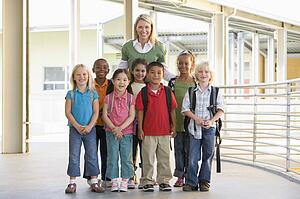Seven students standing with teacher outdoors at school