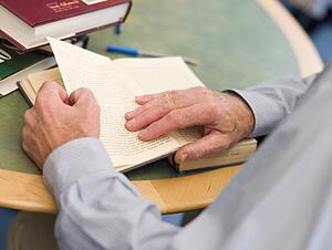Man at table reading a book (selective focus)