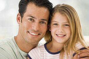 Man and young girl in living room smiling