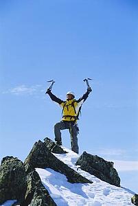 Mountain climber standing on snowy mountain victorious and smiling