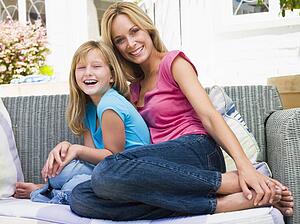Woman and young girl sitting on patio smiling