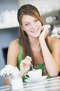 Young woman sitting at a table drinking tea