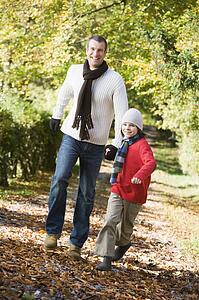 Man and young boy walking outdoors in park and smiling
