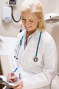 Middle Aged Female Doctor Writing On A Clipboard