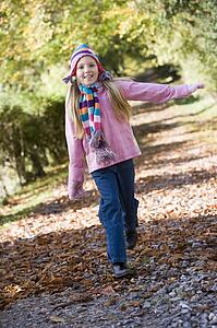 Young girl outdoors at park running on path smiling (selective focus)
