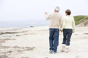 Couple at the beach holding hands and pointing