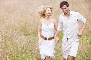 Couple running outdoors holding hands smiling