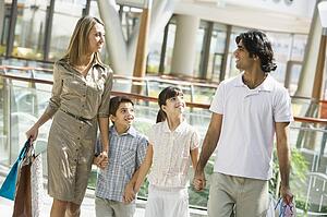Family walking in mall holding hands and smiling (selective focus)