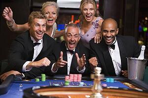Five people in casino playing roulette smiling (selective focus)