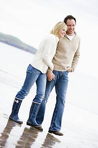 Couple walking on beach holding hands smiling