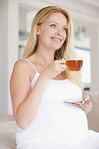 Pregnant woman with cup of tea smiling