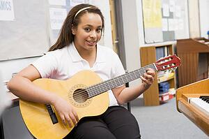 Female student learning guitar in classroom