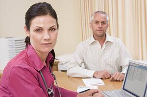 Doctor with laptop and man in doctor's office frowning