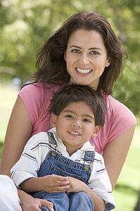 Woman and young boy sitting outdoors smiling