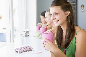 Three young women having a cold drink in a cafeteria