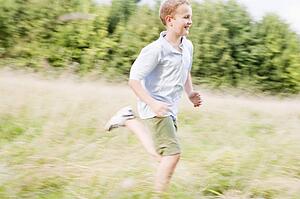 Young boy running in a field smiling