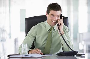 Businessman sitting in office with personal organizer on telephone