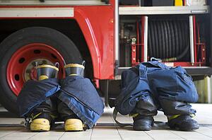 Two firefighting uniforms on floor by fire engine