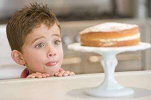 Young boy in kitchen looking at cake on counter
