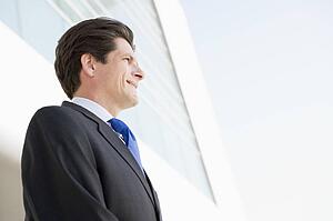 Businessman standing outdoors by building smiling