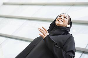 Businesswoman outdoors by building wearing headset and smiling (selective focus)