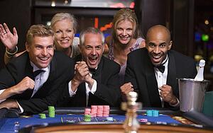 Five people in casino playing roulette smiling (selective focus)