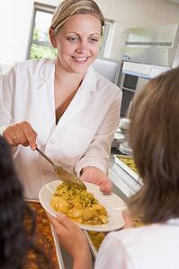 Lunch lady serving rice to student