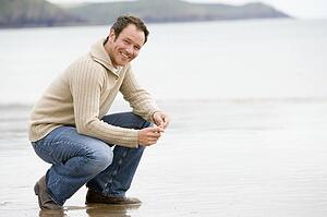 Man crouching on beach smiling