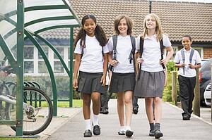Three students leaving school with other students in background