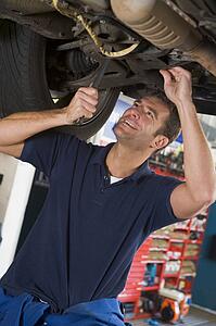 Mechanic working under car smiling