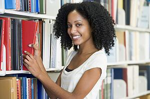 Woman in library pulling book off a shelf (depth of field)
