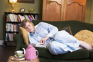 Young woman lying on sofa at home waiting by telephone