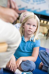 Student in class sitting on floor looking at teacher (selective focus)