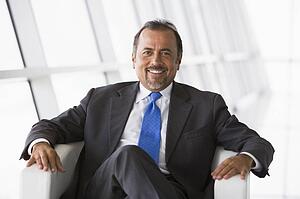 Businessman sitting indoors smiling (high key/selective focus)