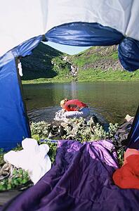 Woman outdoors at campsite by tent splashing water from river on face