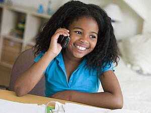 Young Girl Distracted From Her Homework, Talking On A Cellphone
