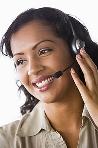 Businesswoman wearing headset in office smiling (high key/selective focus)