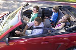 Family in convertible car smiling