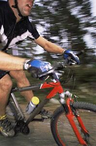 Man outdoors on trails riding bicycle (out of focus)