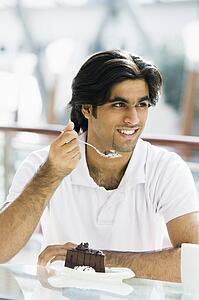 Man at restaurant eating dessert and smiling (selective focus)