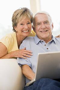 Couple in living room with laptop smiling