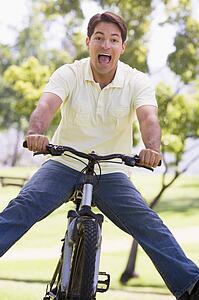 Man outdoors on bike with legs out