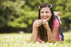Woman lying outdoors with flowers smiling