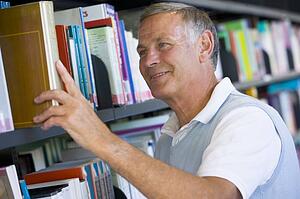 Man in library pulling book off a shelf (depth of field)